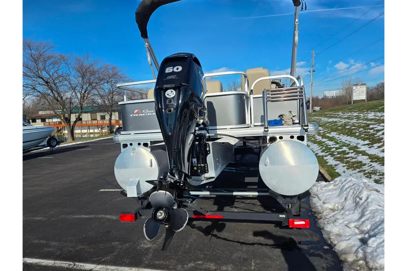 Slide: The Image of 2025 Sun Tracker Party Barge 18 DLX pontoon boat with 60 HP engine, parked outdoors. - 2