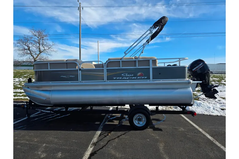 Slide: The Image of 2025 Sun Tracker Party Barge 18 DLX pontoon boat on trailer, parked outdoors. - 4