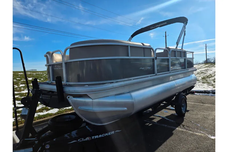 Slide: The Image of 2025 Sun Tracker Party Barge 18 DLX pontoon boat on trailer, parked outdoors. - 5