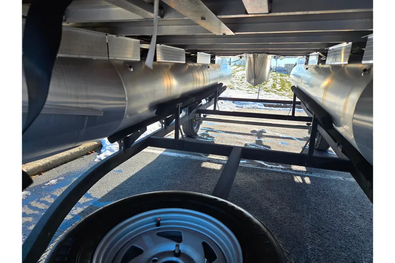 Slide: The Image of Underneath view of 2025 Sun Tracker Party Barge 18 DLX pontoon boat on trailer. - 7