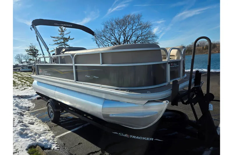 Slide: The Image of 2025 Sun Tracker Party Barge 18 DLX pontoon boat on trailer by a lake. - 8