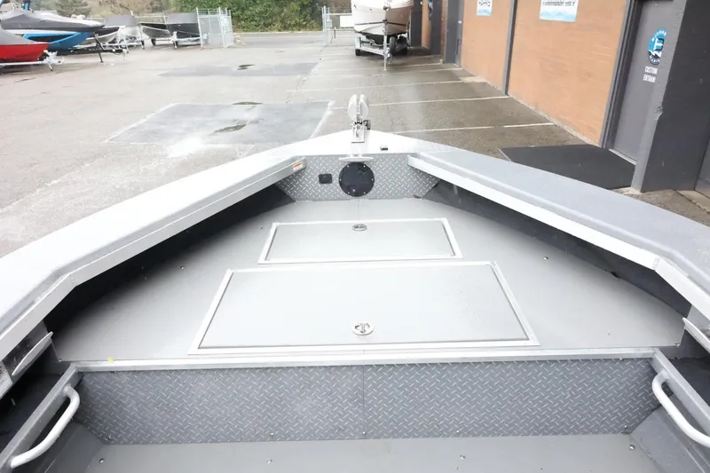 Slide: The Image of 2025 Thunder Jet 209 Rush OT boat interior with storage compartments, parked outdoors. - 12