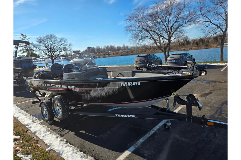 Slide: The Image of 2020 Tracker Pro Guide V-16 SC boat on trailer by a lake, parked in a lot. - 9