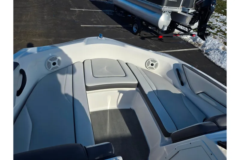 Slide: The Image of 2020 Yamaha Boats SX190 interior with gray seating and speakers, parked on pavement. - 17