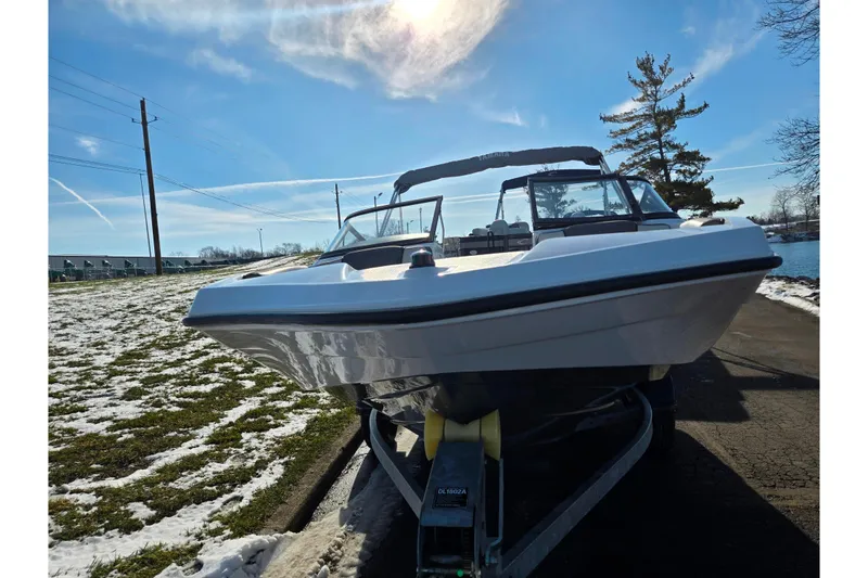 Slide: The Image of 2020 Yamaha Boats SX190 on trailer, parked near snowy lakeside under clear blue sky. - 6