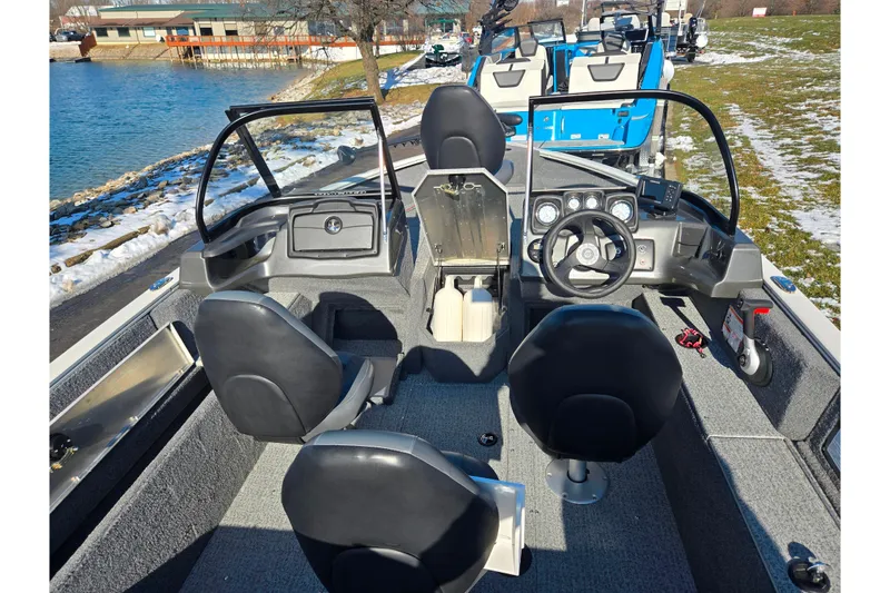Slide: The Image of 2021 Tracker Pro Guide V-165 WT boat interior with steering wheel and seating, near a lake. - 11