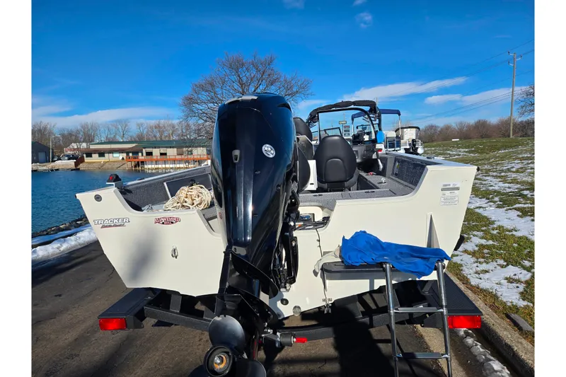 Slide: The Image of 2021 Tracker Pro Guide V-165 WT boat with outboard motor on trailer by a lake. - 2