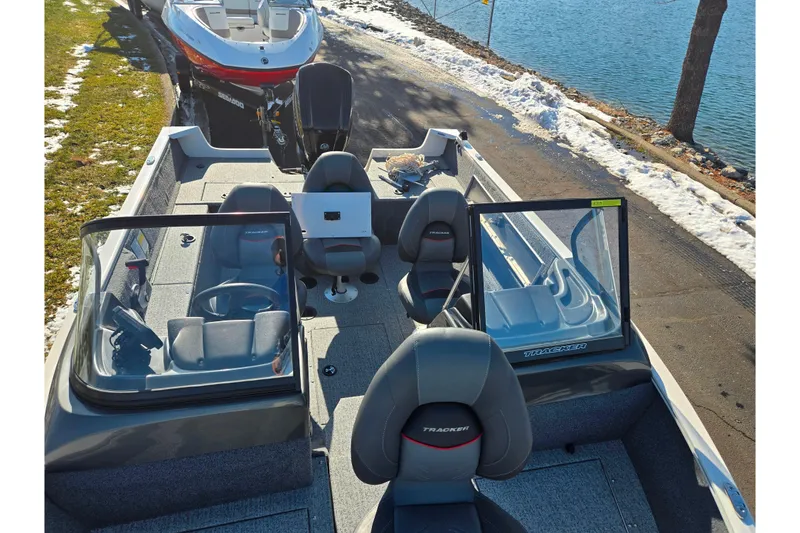 Slide: The Image of 2021 Tracker Pro Guide V-165 WT boat interior with seating and steering wheel by a lake. - 23