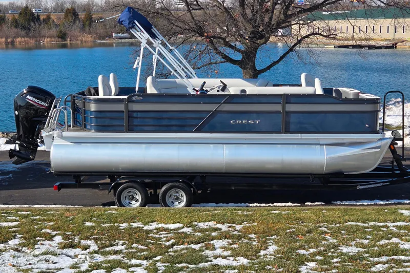 The Image of 2022 Crest Classic Fish 200 pontoon boat on trailer by a lake. - 0