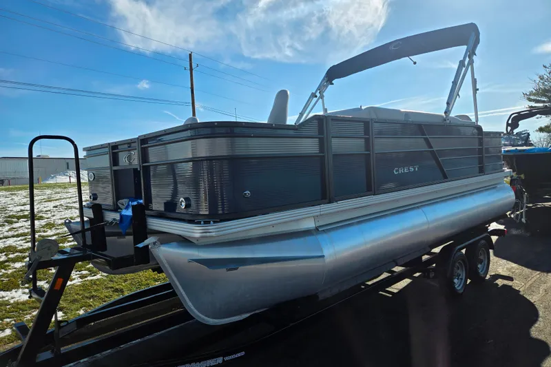 Slide: The Image of 2022 Crest Classic Fish 200 pontoon boat on trailer under clear blue sky. - 5