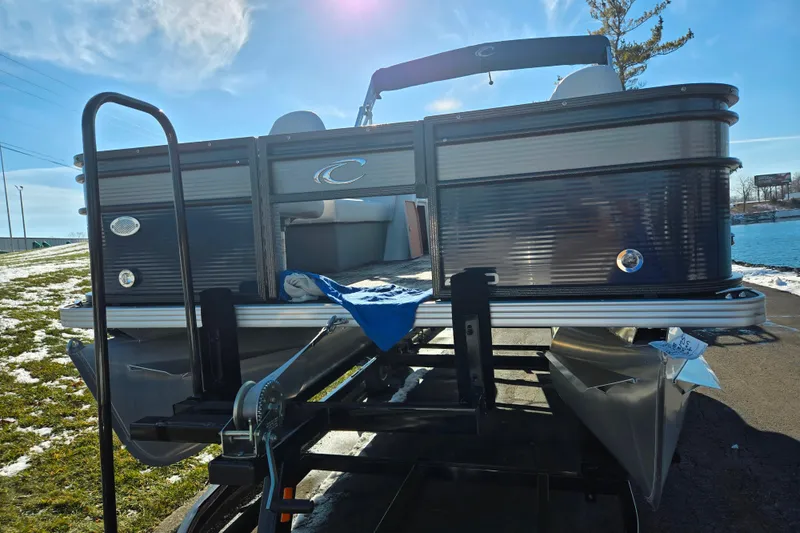 Slide: The Image of 2022 Crest Classic Fish 200 pontoon boat on trailer, sunny day, lakeside view. - 6