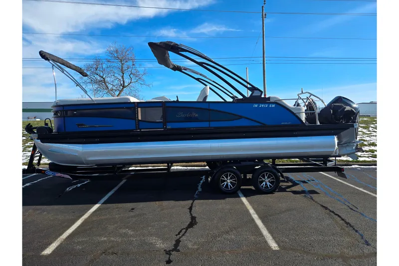Slide: The Image of 2023 Barletta Corsa 23UC pontoon boat on trailer, parked in a lot. - 4