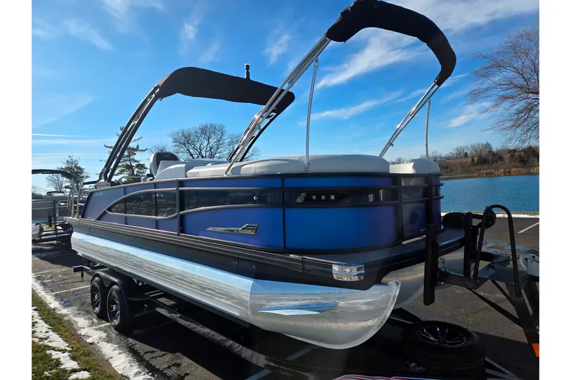 Slide: The Image of 2023 Barletta Corsa 23UC pontoon boat on trailer by a lake. - 9
