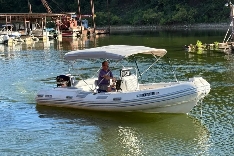 Slide: The Image of Man driving a 2005 Caribe DL20 inflatable boat on a calm lake. - 1
