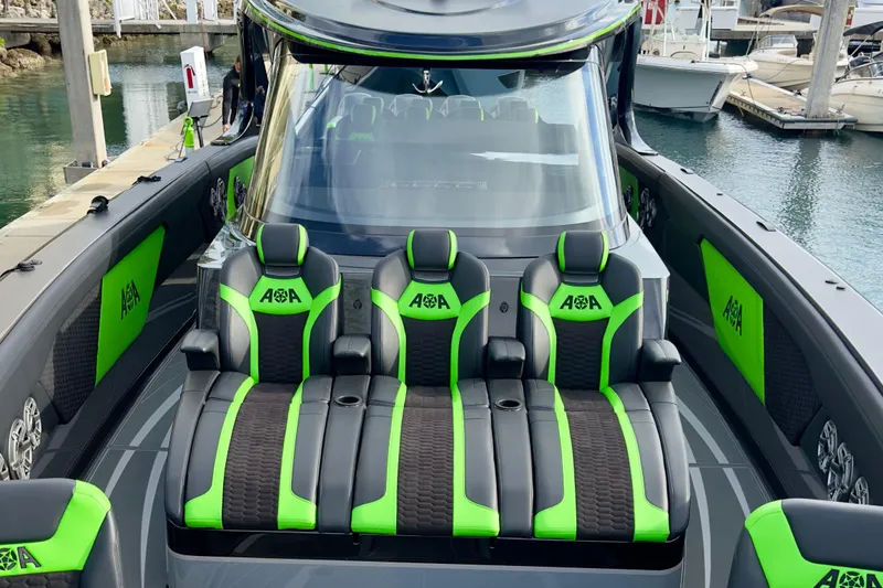 Slide: The Image of 2026 Mystic Powerboats M5200 XL Cabin with sleek green and black seating at a marina. - 17