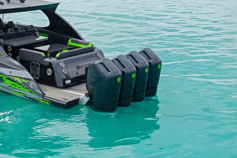 Slide: The Image of 2026 Mystic Powerboats M5200 XL Cabin with quad engines on turquoise water. - 38