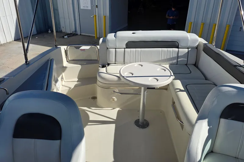 Slide: The Image of 2010 Sea Ray 260 Sundeck interior with seating and table, docked near a building. - 13