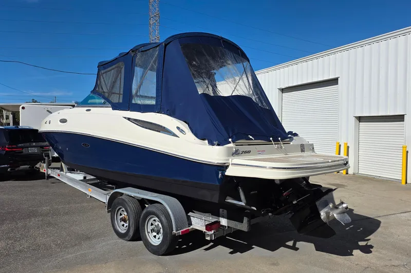 Slide: The Image of 2010 Sea Ray 260 Sundeck boat on trailer, blue and white exterior, covered cockpit. - 5
