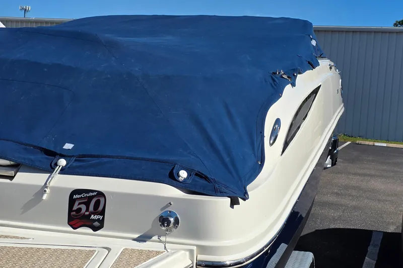 Slide: The Image of 2010 Sea Ray 260 Sundeck boat with blue cover, parked outdoors. - 54
