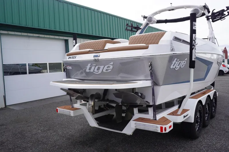 Slide: The Image of 2023 Tigé 24RZX boat on trailer, parked outside a green building. - 11