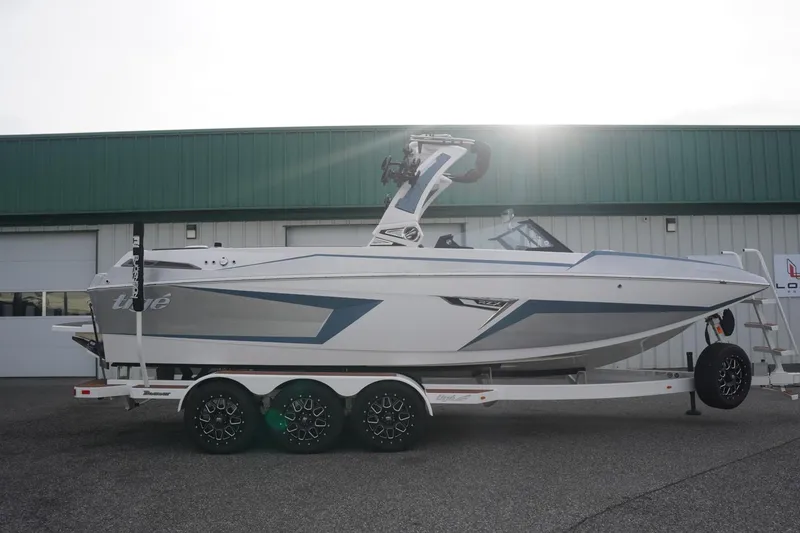 Slide: The Image of 2023 Tigé 24RZX boat on trailer, parked outside a green-roofed building. - 12