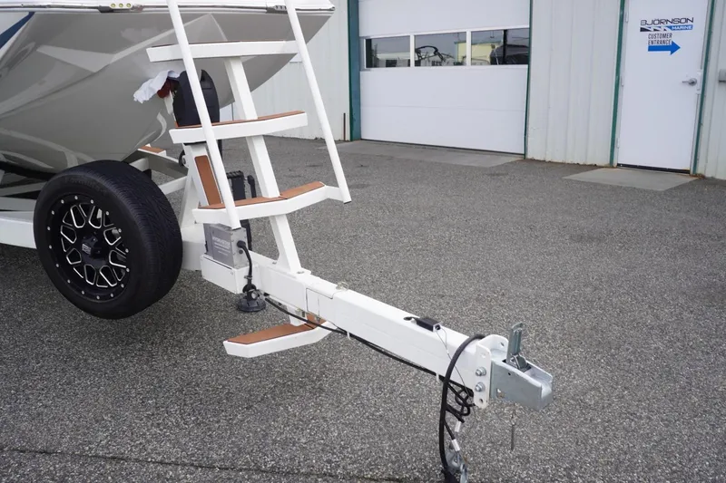 Slide: The Image of 2023 Tigé 24RZX boat trailer with ladder and black wheel, parked outside. - 19