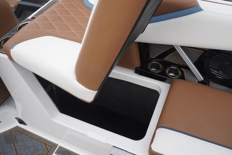 Slide: The Image of 2023 Tigé 24RZX boat interior with brown and white seating, cup holders, and storage compartment. - 64