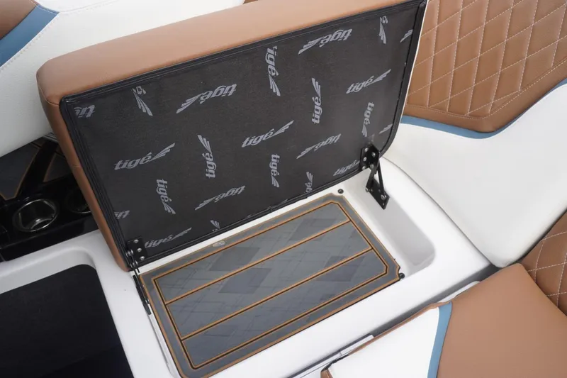 Slide: The Image of 2023 Tigé 24RZX boat seat storage with brown and white upholstery, open compartment. - 66