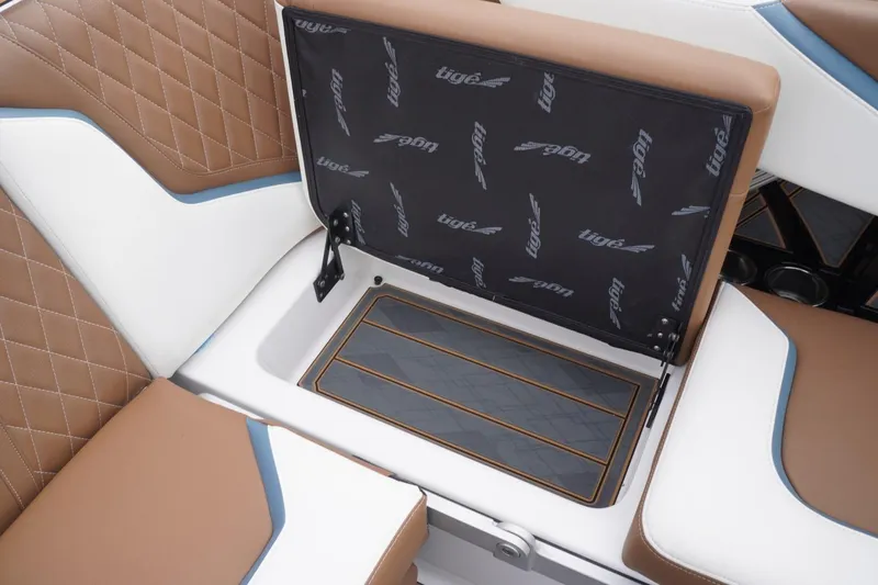 Slide: The Image of 2023 Tigé 24RZX boat interior with brown and white seating, open storage compartment. - 67