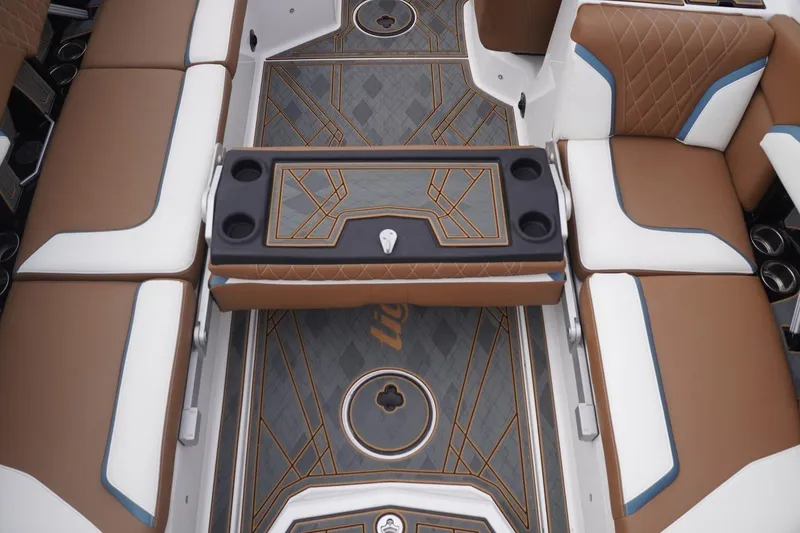Slide: The Image of 2023 Tigé 24RZX interior with brown and white seating, geometric flooring, and cup holders. - 82