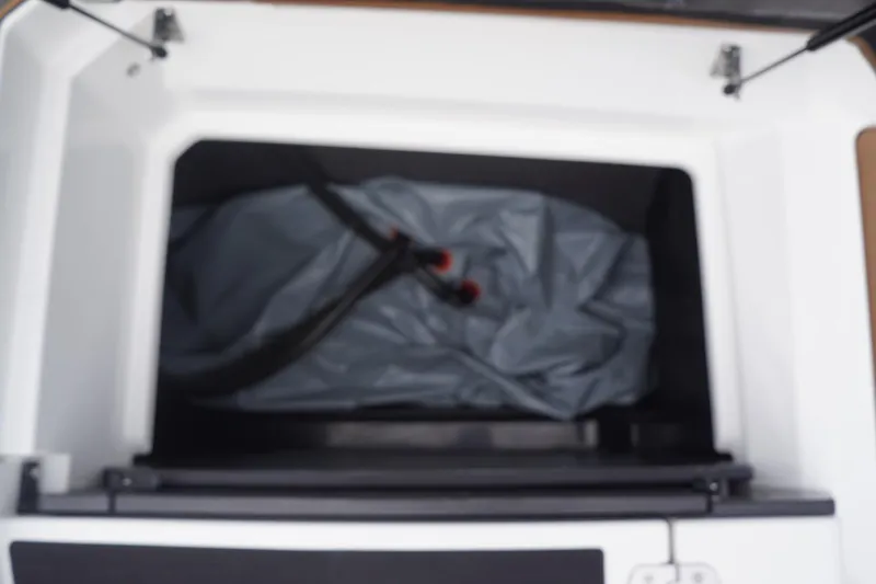 Slide: The Image of 2023 Tigé 24RZX storage compartment with gray cover and black hose. - 84