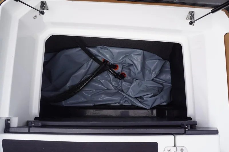 Slide: The Image of 2023 Tigé 24RZX storage compartment with gray cover and black hose. - 85