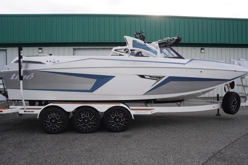 Slide: The Image of 2023 Tigé 24RZX boat on trailer, sleek design, parked outside green building. - 97