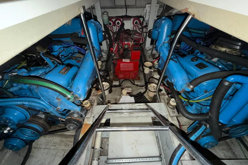 Slide: The Image of Engine room of 1989 Tiara Yachts 3600 Open, featuring twin blue engines and red generator. - 47