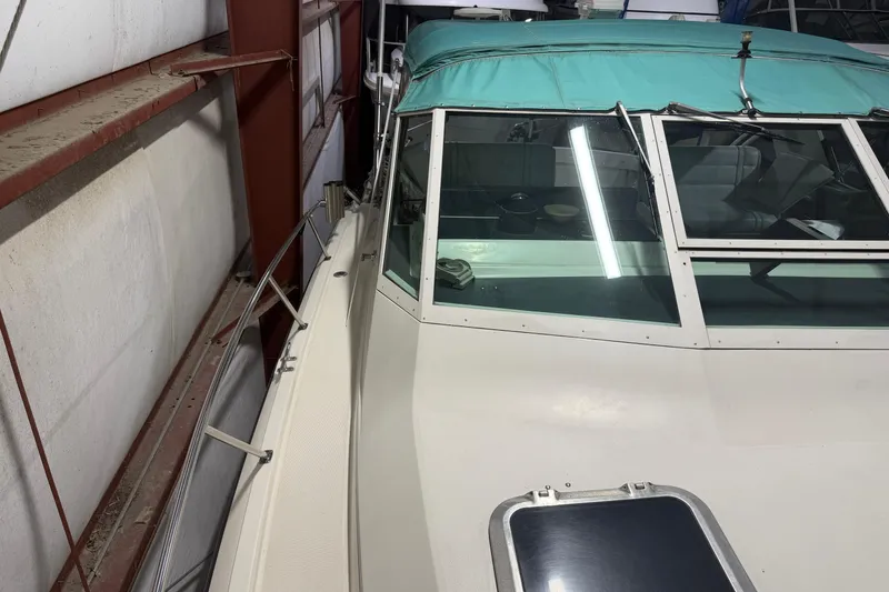 Slide: The Image of 1989 Tiara Yachts 3600 Open in storage, featuring teal canopy and sleek design. - 7