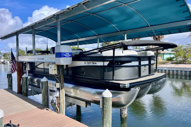 Slide: The Image of 2023 Barletta Corsa 23UC pontoon boat docked under a blue canopy. - 5