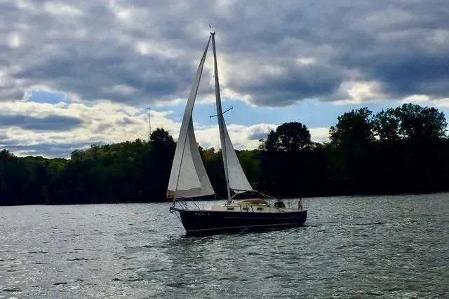 The Image of 2019 Com-Pac 23/IV sailboat on a lake under cloudy skies. - 0