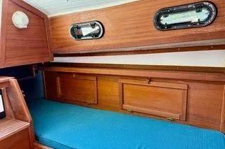 Slide: The Image of 2019 Com-Pac 23/IV sailboat interior with wooden finish and blue cushion. - 12