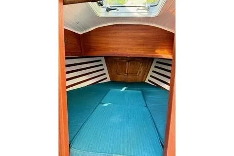 Slide: The Image of 2019 Com-Pac 23/IV sailboat interior with blue cushions and wooden accents. - 18