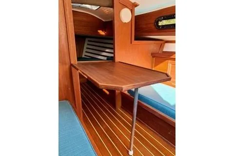 Slide: The Image of 2019 Com-Pac 23/IV sailboat interior with wooden table and seating area. - 7