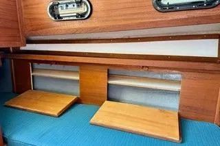 Slide: The Image of Interior of 2019 Com-Pac 23/IV sailboat with wooden shelves and blue seating. - 9