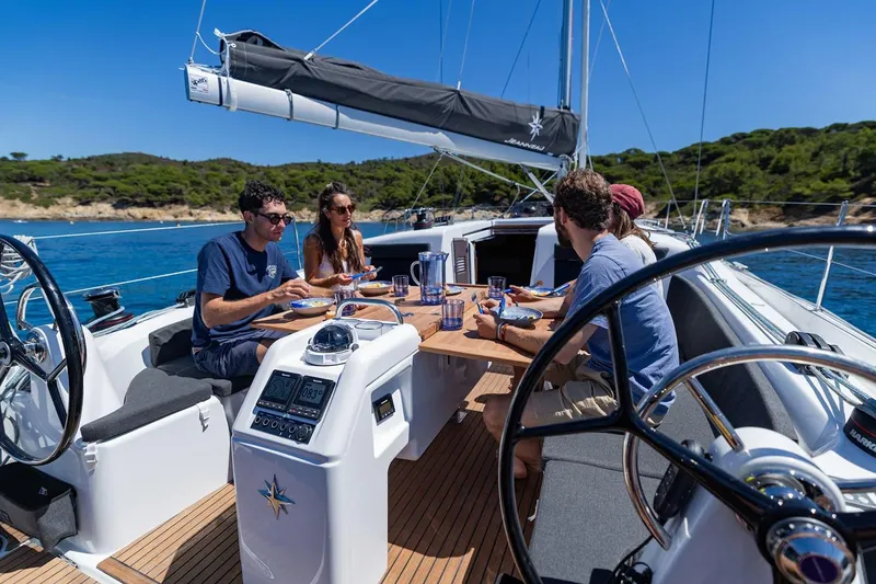 Slide: The Image of Manufacturer Provided Image: People dining on Jeanneau Sun Odyssey 415 sailboat, 2025 model, in scenic coastal setting. - 2