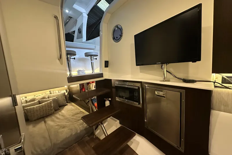 Slide: The Image of 2024 Cruisers Yachts 38 GLS OB interior with TV, microwave, and cozy sleeping area. - 16