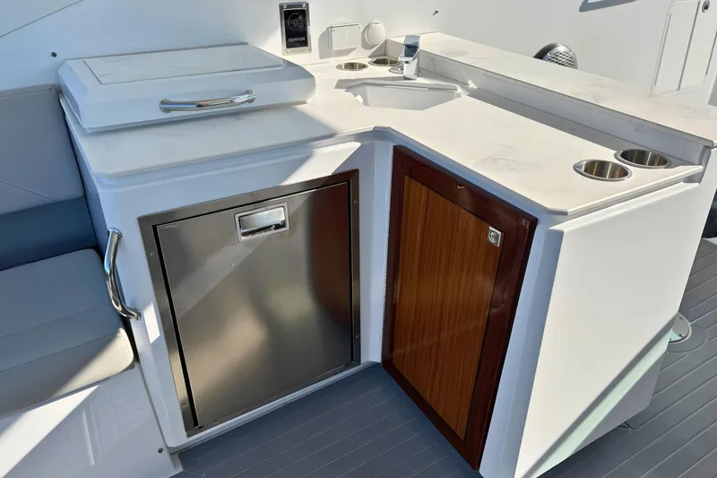 Slide: The Image of 2024 Cruisers Yachts 38 GLS OB boat kitchenette with sink, storage, and stainless steel fridge. - 21