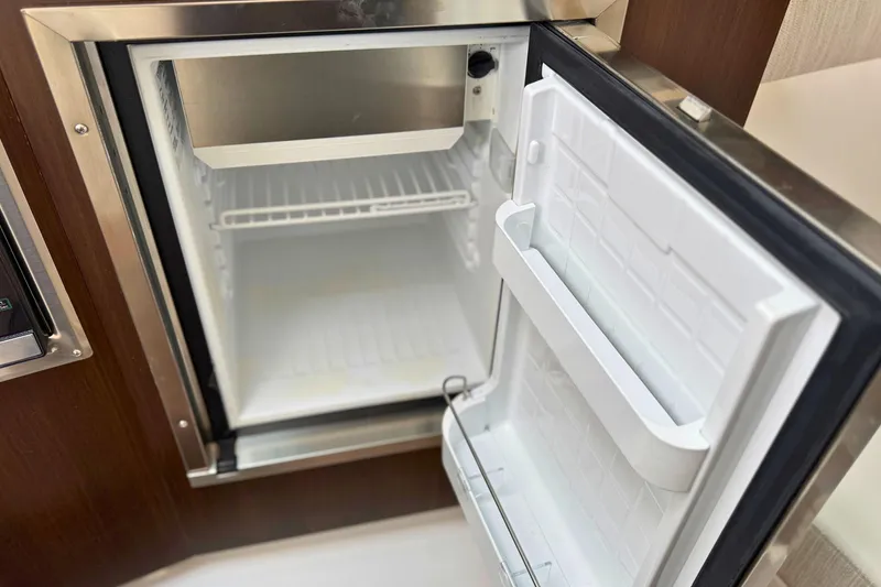 Slide: The Image of Open refrigerator inside 2024 Cruisers Yachts 38 GLS OB, showcasing interior storage space. - 48