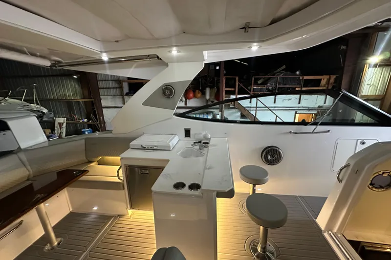 Slide: The Image of 2024 Cruisers Yachts 38 GLS OB interior with seating, bar stools, and ambient lighting. - 6