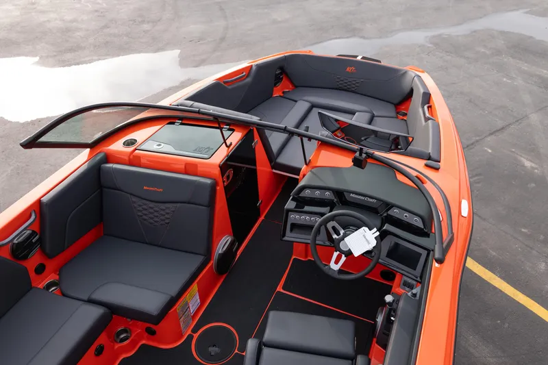 Slide: The Image of 2026 MasterCraft NXT24 boat interior with orange and black seating and modern dashboard design. - 13
