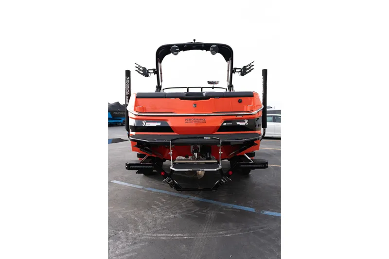 Slide: The Image of 2026 MasterCraft NXT24 boat, rear view, vibrant orange color, parked on pavement. - 6