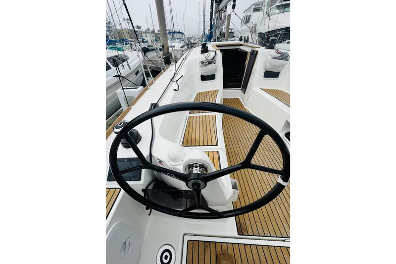Slide: The Image of 2024 Jeanneau Sun Odyssey 349 sailboat docked in a marina, featuring dual steering wheels. - 22