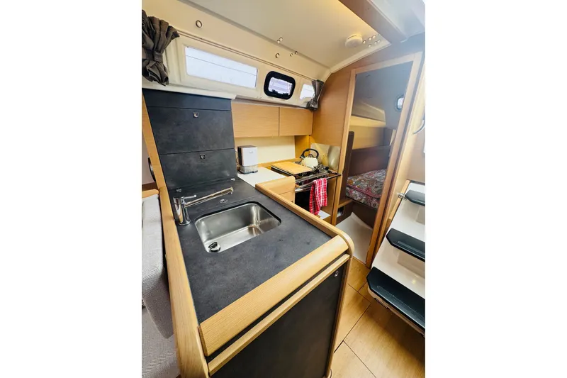 Slide: The Image of 2024 Jeanneau Sun Odyssey 349 interior kitchen with sink, stove, and wooden cabinetry. - 35
